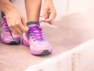 Retro woman tying shoes laces. Closeup of female sport fitness runner getting ready for outdoor jogging. Fitness and sport concept.