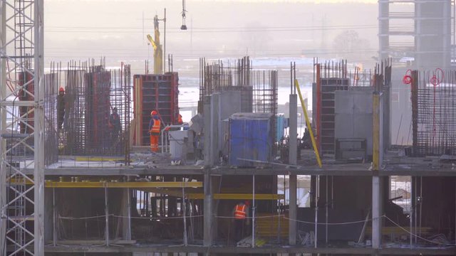 Builders on the top floor of the new building install formwork for the formation of a new floor, long shot