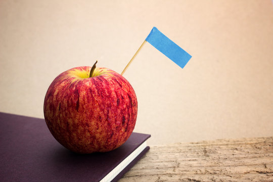 Red apples put on the book with brown as the background