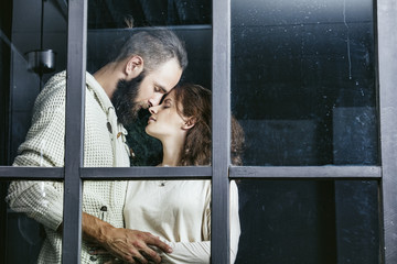 Young beautiful heterosexual couple man and woman lovers embrace outside the window