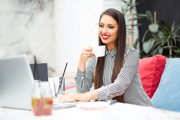 Casual woman using laptop at coffee shop
