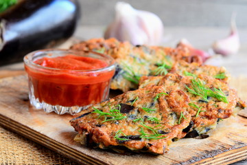 Eggplant burgers with garlic and dill on a wooden board. Tomato sauce in a glass bowl. Vegetarian eggplant burgers recipe. Closeup