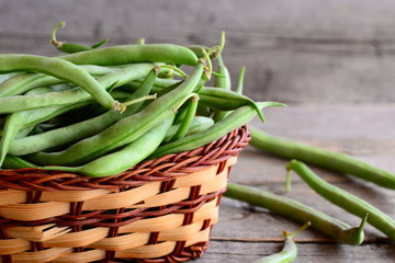 Fresh green string beans in a wicker basket. Young green beans, good source of fiber, vitamins and...