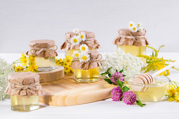 Fototapeta na wymiar Honey in a jar, flowers and honey dipper on white background