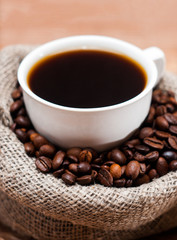 Cup of coffee in a bag of grains