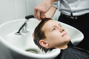 a boy is washed by the hairdresser in the barbershop