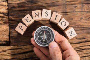 Hand Holding Compass On Pension Block