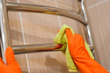 A woman washer is cleaning tiled surface in bathroom.