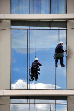 Sich abseilende Fensterputzer an der Glasfassade eines Wolkenkratzers