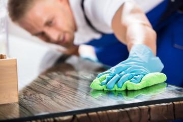 Close-up Of A Janitor Cleaning Desk With Cloth