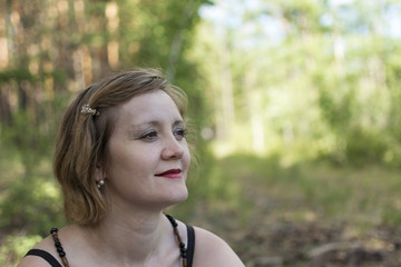 Fototapeta premium girl is looking to the sky. Woman looking sideways in a park in summer