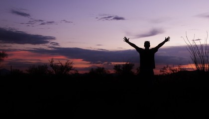 Silhouette of a man praying under a beautiful Arizona sunset.