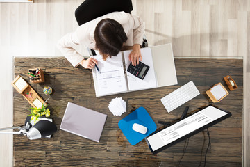 Businesswoman Calculating Invoice In Office