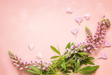Romantic background with lupine flowers and decorative hearts on a pink.