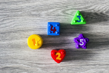 Colorful plastic shapes with numbers on a wooden background