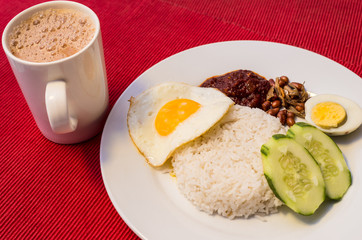 Malaysian Food - Nasi Lemak and Frothy Teh Tarik on a red background. Both dishes are unofficially the national breakfast dish of Malaysia. Teh tarik is basically a Tea with Milk