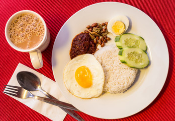 Malaysian Food - Nasi Lemak and Frothy Teh Tarik on a red background. Both dishes are unofficially the national breakfast dish of Malaysia. Teh tarik is basically a Tea with Milk