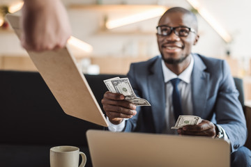 handsome african american businessman paying with cash in cafe
