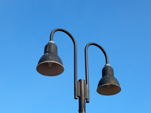 Two street lamps in the daytime against the background of clear blue sky