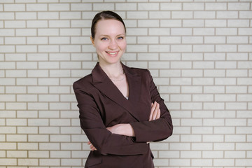 Attractive girl in a suit on a white brick wall background. Business concept.