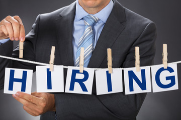Businessman Pinning HIRING Cards On Clothesline
