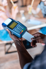 cropped view of african american waiter with terminal taking payment with credit card in cafe