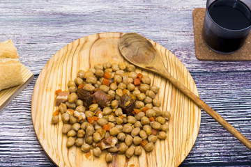 Madrid stew on a plate on a wooden table With bread and a glass of red wine, typical food from Spain