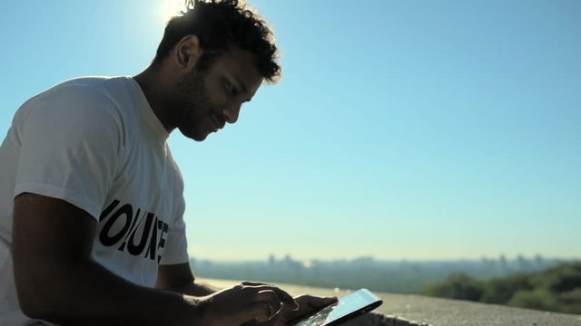 Cheerful male volunteer using the tablet outdoors