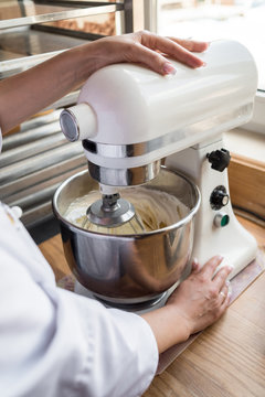 Close Up Of Young Woman Using Kitchen Mixer Preparing Dough For Sweet Cake