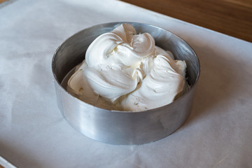 Form for baking cake with dough on baking tray with parchment paper. Dough for homemade cake in metal dish on the table