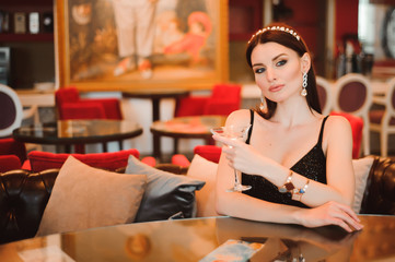 A beautiful girl drinks martini in the hotel lobby and is waiting for her young boyfriend