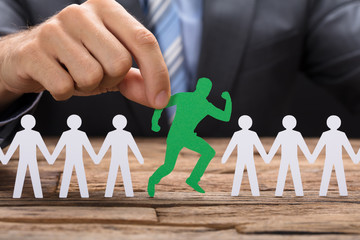 Businessman Holding Green Paperman Standing Out From Crowd