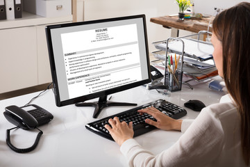 Businesswoman Looking At Resume On Computer