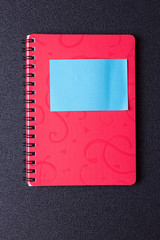 Red notepad on a spiral with a sticker