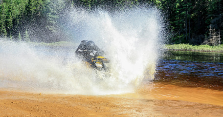 Man driving ATV quad through splashing water with high speed. © Drepicter