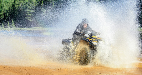 Man driving ATV quad through splashing water with high speed. © Drepicter
