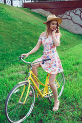 Young beautiful woman with yellow bicycle in a park. Active people spending time outdoors.