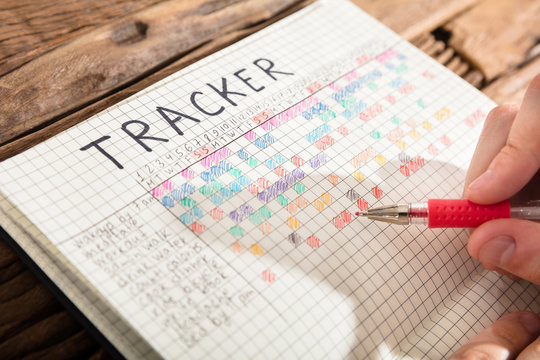Person Drawing Tracker Chart On Notebook