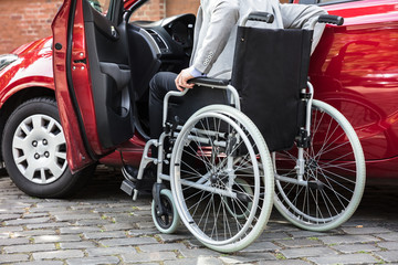 Fototapeta premium Man Sitting In Car Folding His Wheelchair