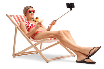 Young woman in a deck chair taking a selfie