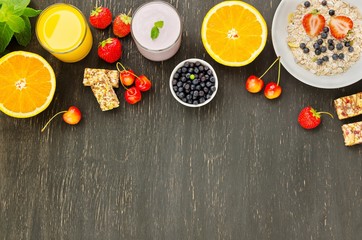 Healthy breakfast of muesli, berries with yogurt and orange juice on dark background.