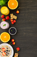 Healthy breakfast of muesli, berries with yogurt and orange juice on dark background.