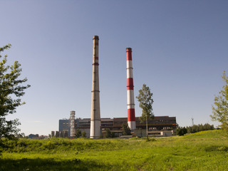 Fototapeta na wymiar Industrial enterprises on the background of blue sky and green grass