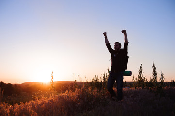 Young man is looking at sunset. Traveller with backpack.