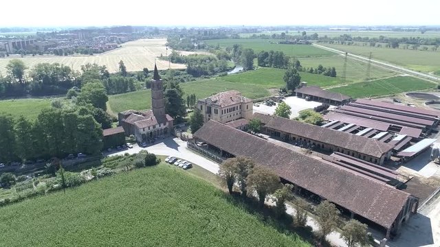 Aerial drone video of the typical Italian countryside, with an old romanic church and a farm