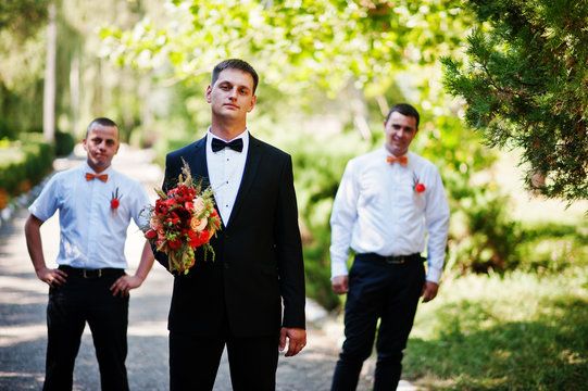 Handsome groom walking with his bestmen or groomsmen in the park on a wedding day.