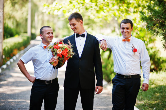 Handsome groom walking with his bestmen or groomsmen in the park on a wedding day.
