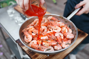 Fried king prawns on iron pan. the chef pours hot sauce