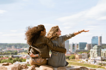 Two female friends waving hands and enjoying city skyline