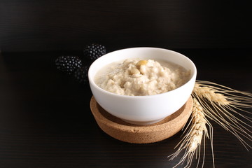 Oat porridge with blackberries, ears of corn on a dark background